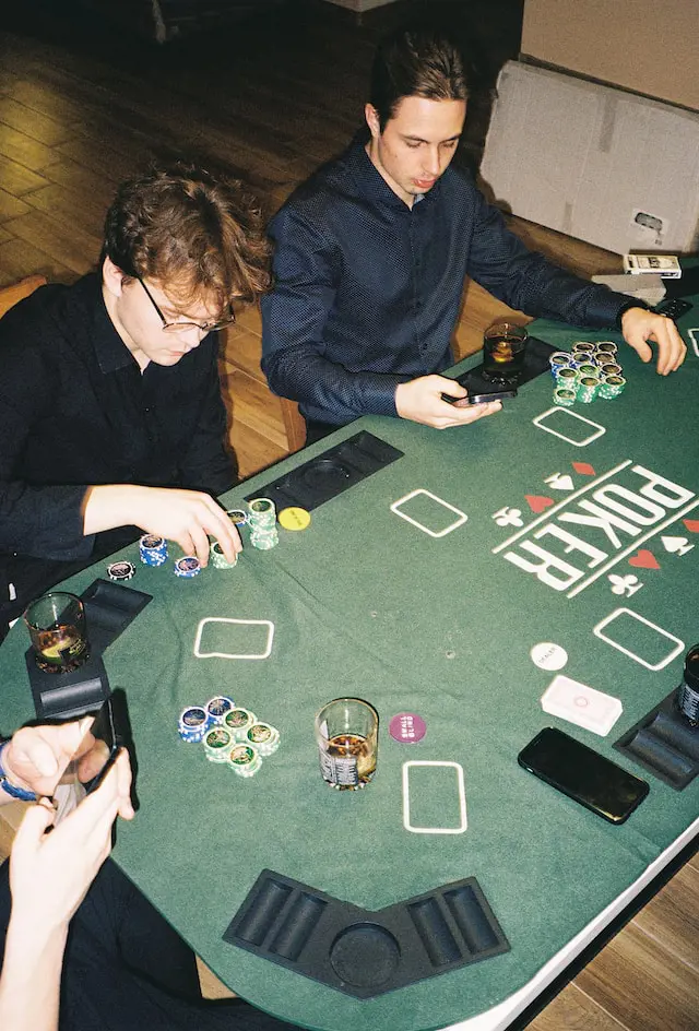 Two men sitting at a table and playing Poker.